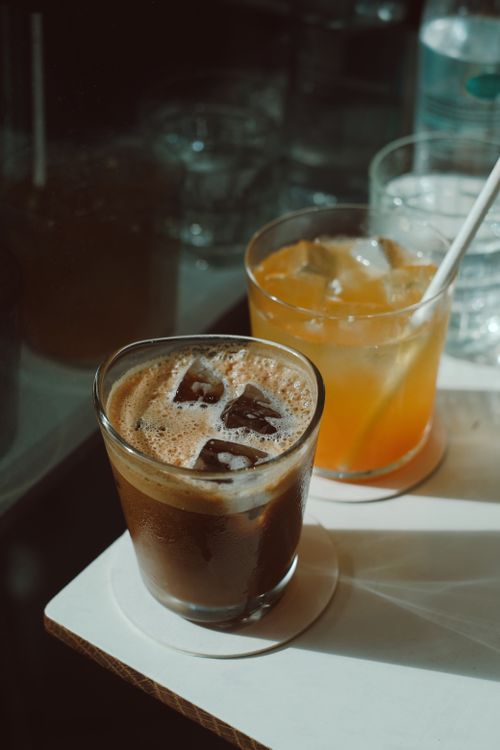 Free Close-up of iced coffee and citrus drink in sunlight on a wooden table. Stock Photo