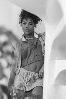 Black and white portrait of a stylish woman in a denim outfit, featuring elegant curls and confident pose.