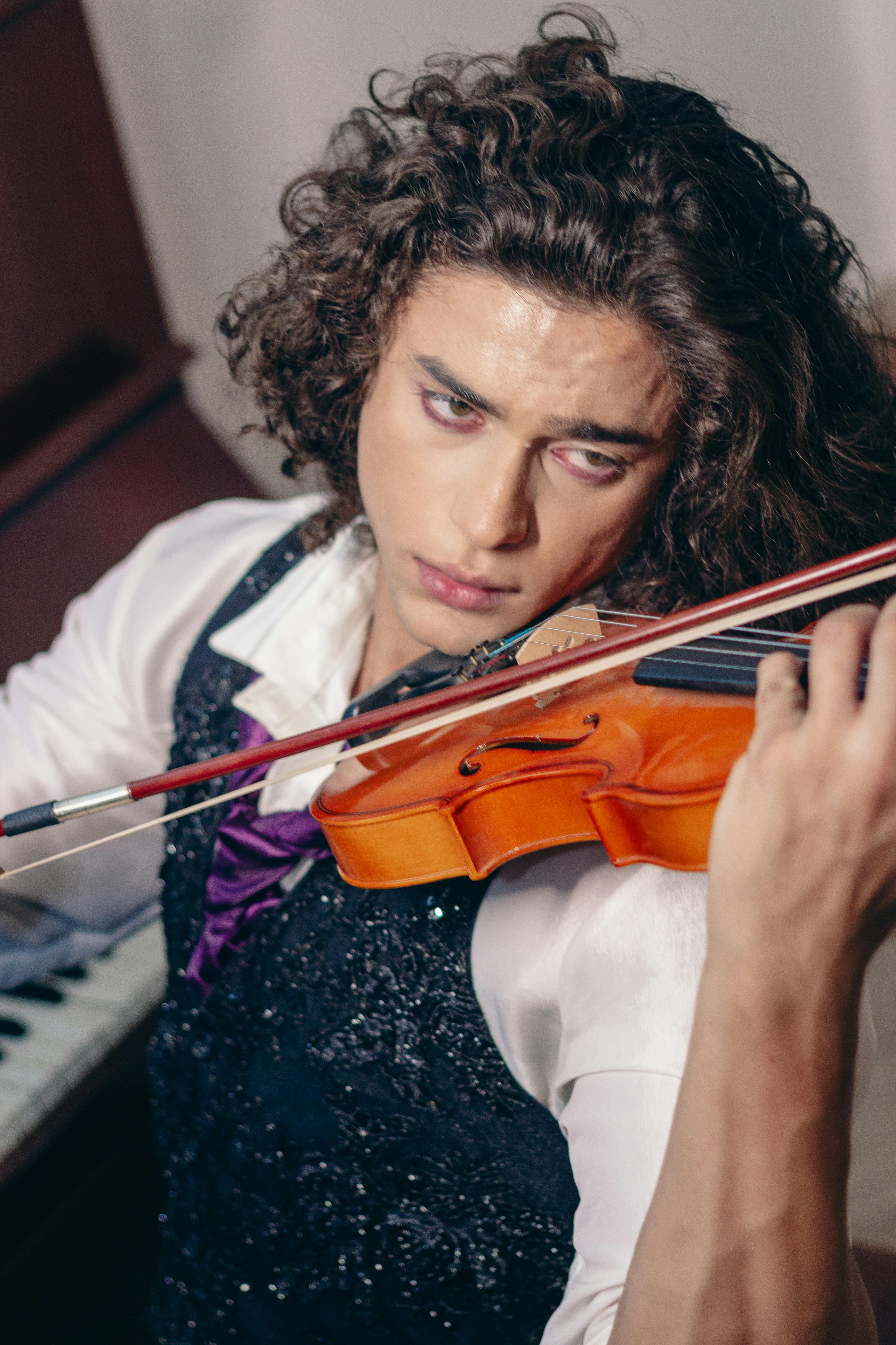 A focused young man passionately playing the violin indoors.