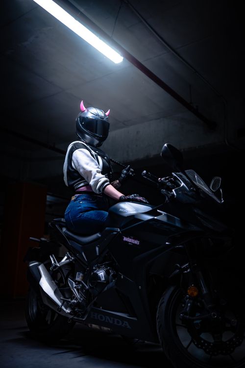 Free A motorcyclist wearing a helmet with horns sits on a sleek, dark motorcycle indoors. Stock Photo
