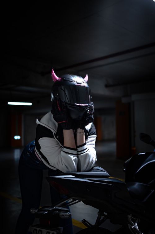 Free Mystery biker with devil horns helmet in dimly lit garage. Stock Photo
