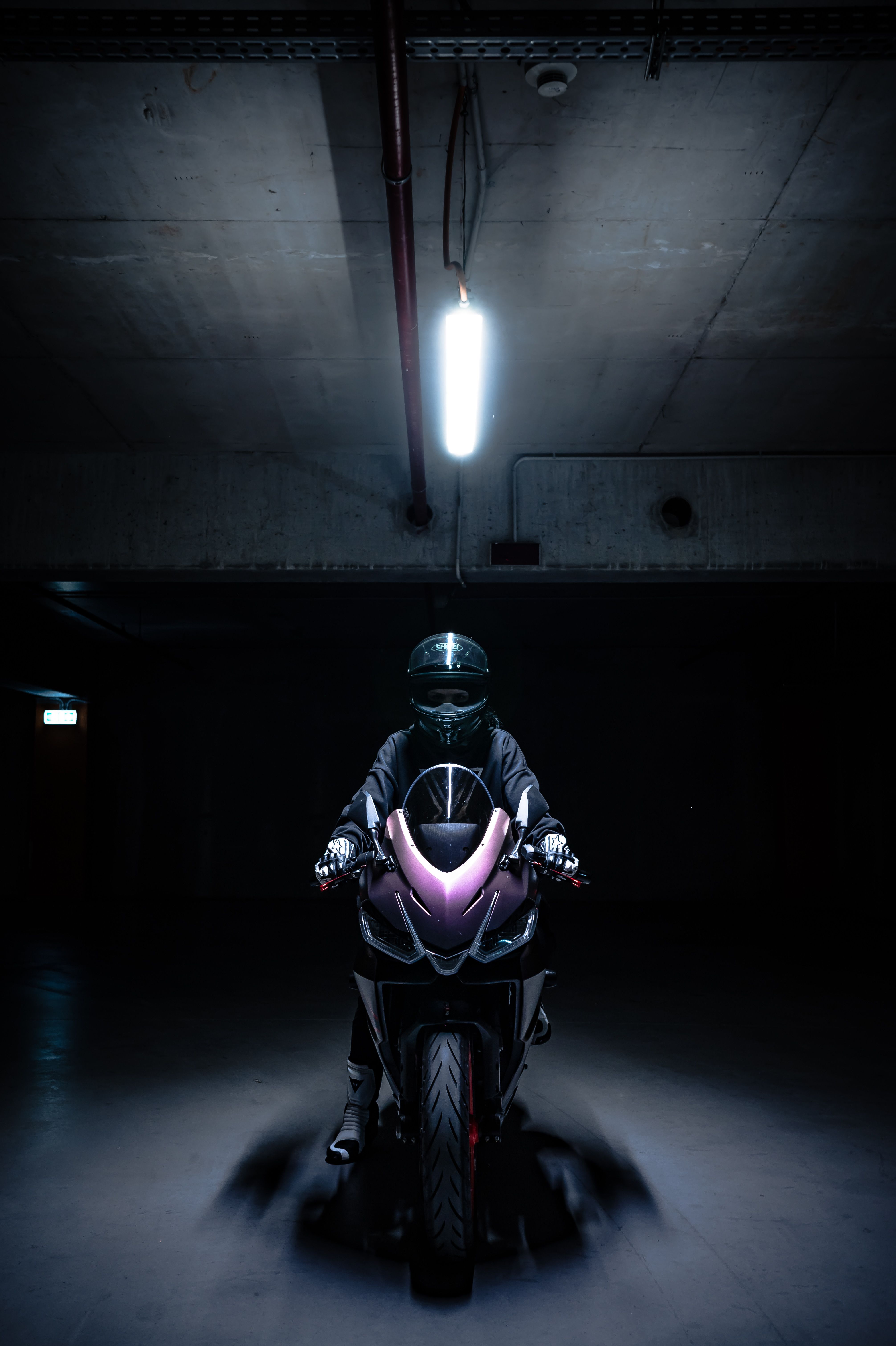 Dramatic Motorcycle Rider in Dark Parking Garage · Free Stock Photo