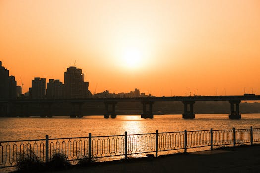 A beautiful sunset over a city bridge and river silhouette, casting warm tones.