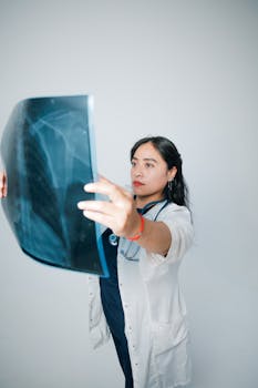 A female doctor in a white coat examines a patient's X-ray image against a neutral background.