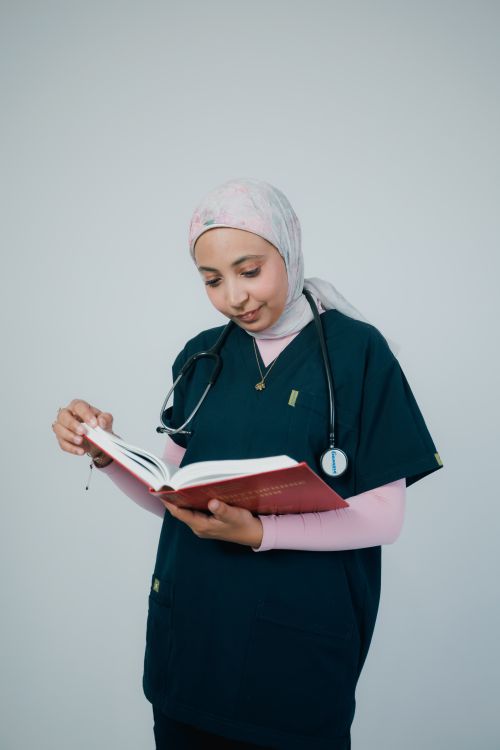 Free Medical professional in scrubs reading a book with focus and concentration. Stock Photo