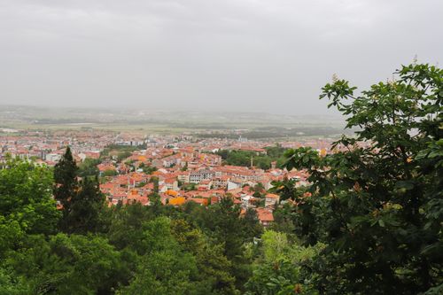 Free Overlooking a European town with red rooftops surrounded by green hills and trees. Stock Photo