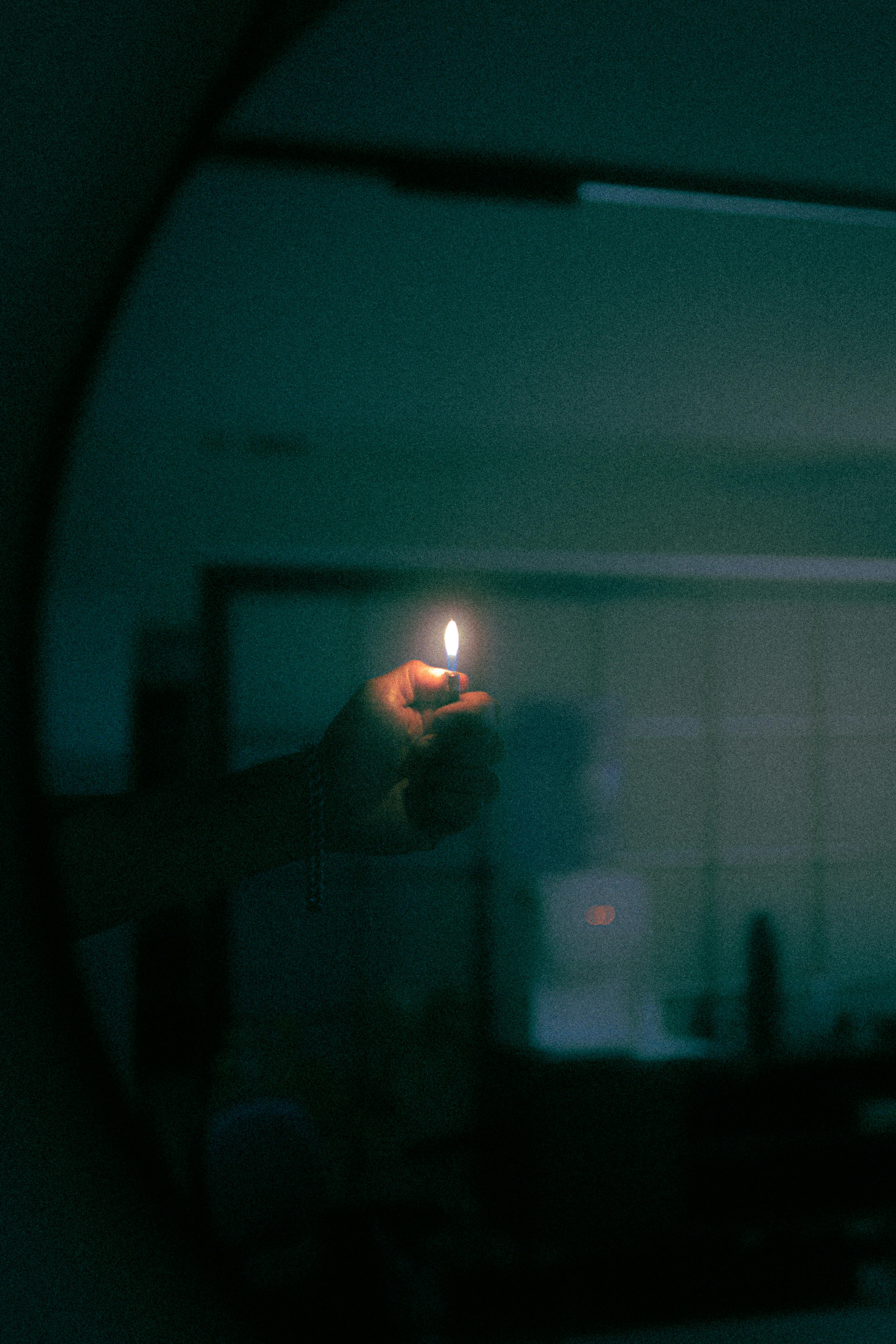 A mysterious, dimly lit room with a hand holding a lit lighter, casting a warm glow.