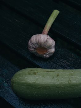 Close-up of fresh garlic and zucchini on a dark rustic table, perfect for culinary themes.