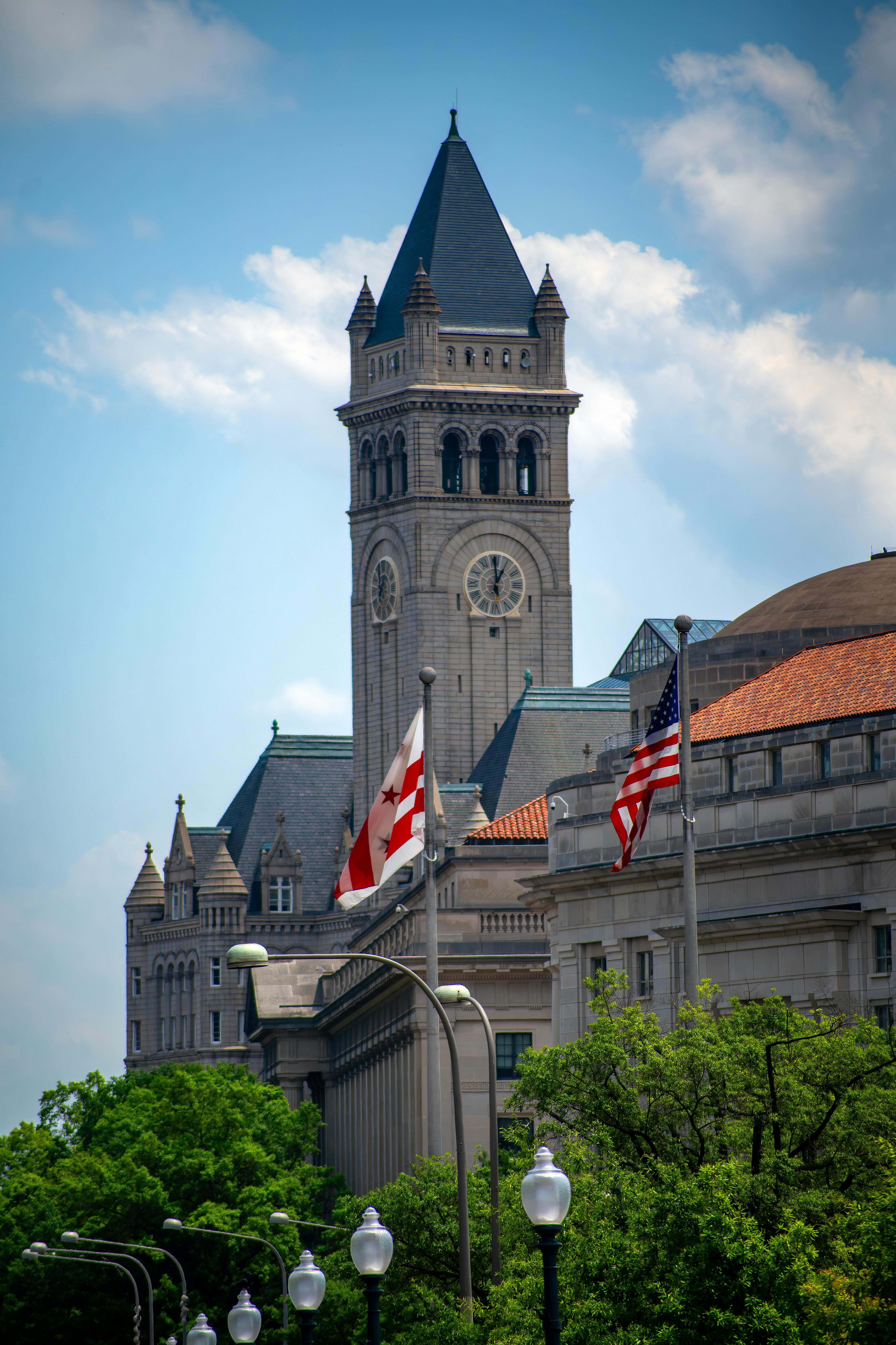 Iconic Old Post Office Tower with surrounding flags in Washington, D.C., on a sunny day.