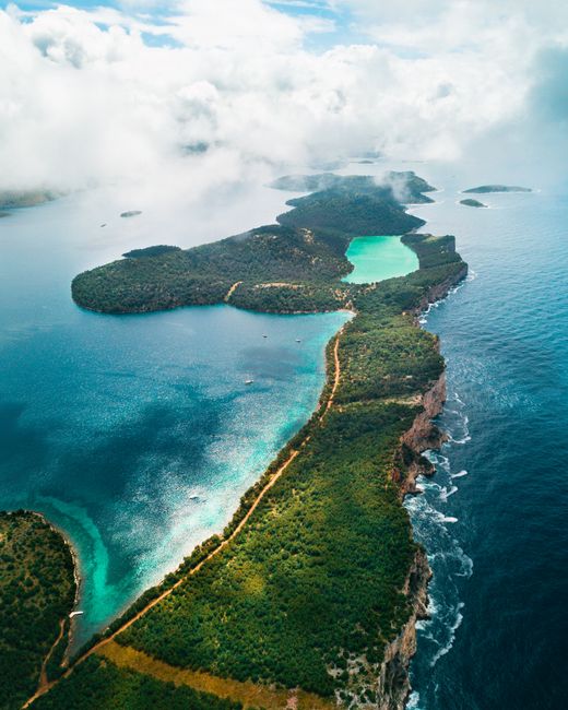 Drone shot capturing a tranquil coastal landscape with lush greenery and turquoise waters.