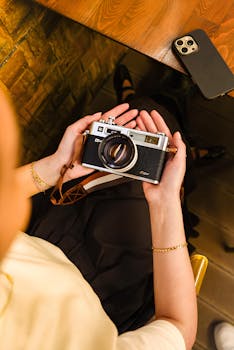 Person holding vintage camera, capturing creative moments indoors.