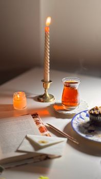 Relaxing candlelit setup with tea, book, and muffin for a peaceful evening.