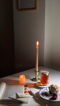 Inviting candlelit scene with tea, open book, and dessert for a relaxing evening.