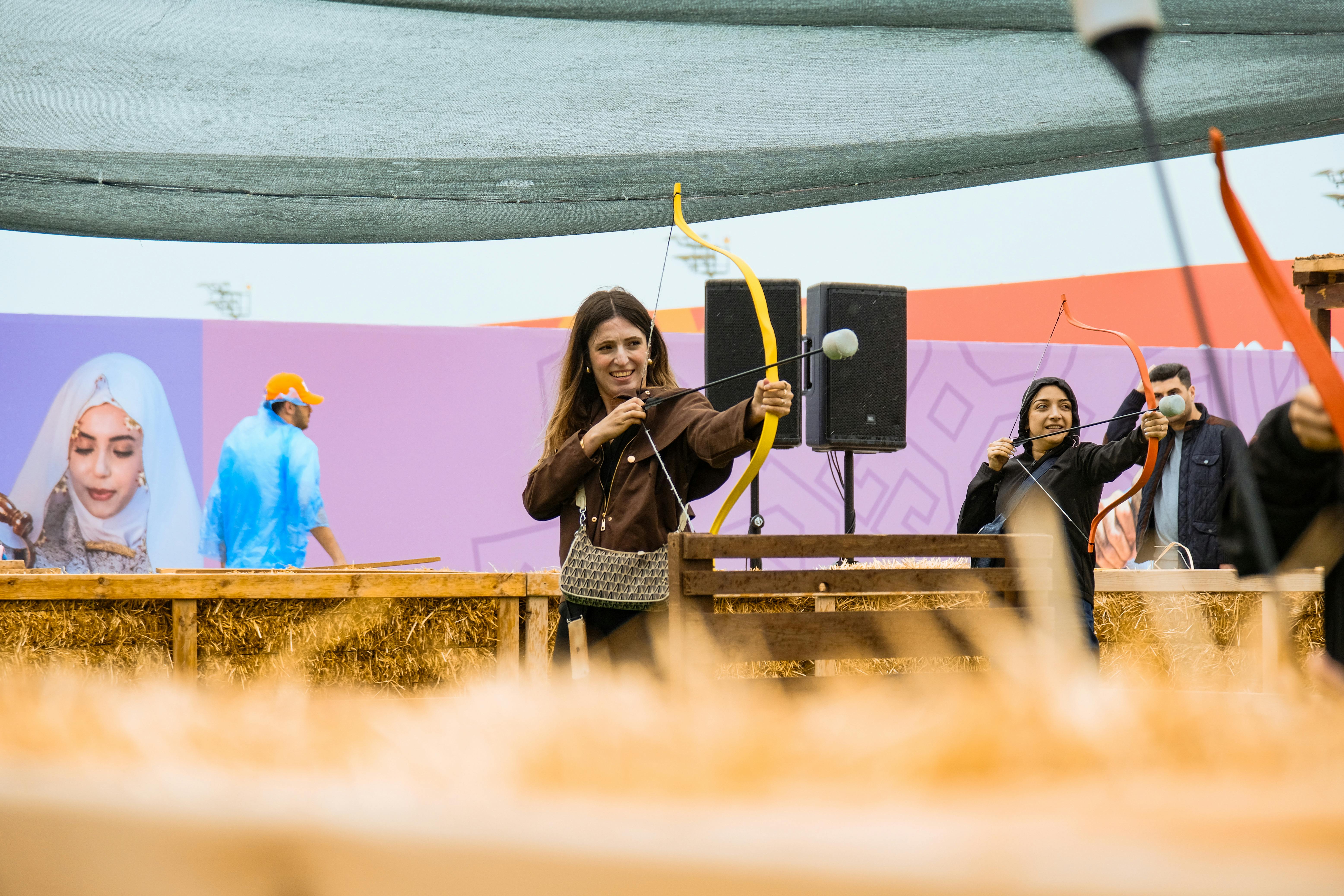 Adults practice archery at an outdoor event, showcasing skill and fun.