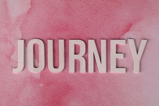 Inspirational word 'Journey' on textured pink background, evoking adventure and personal growth.