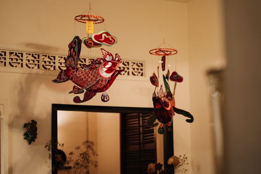 Vibrant fish-shaped lanterns hanging inside a warmly lit room, symbolizing celebration.