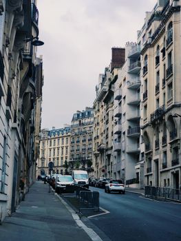 Charming view of a Parisian street with classic buildings and cars parked along the sidewalk.