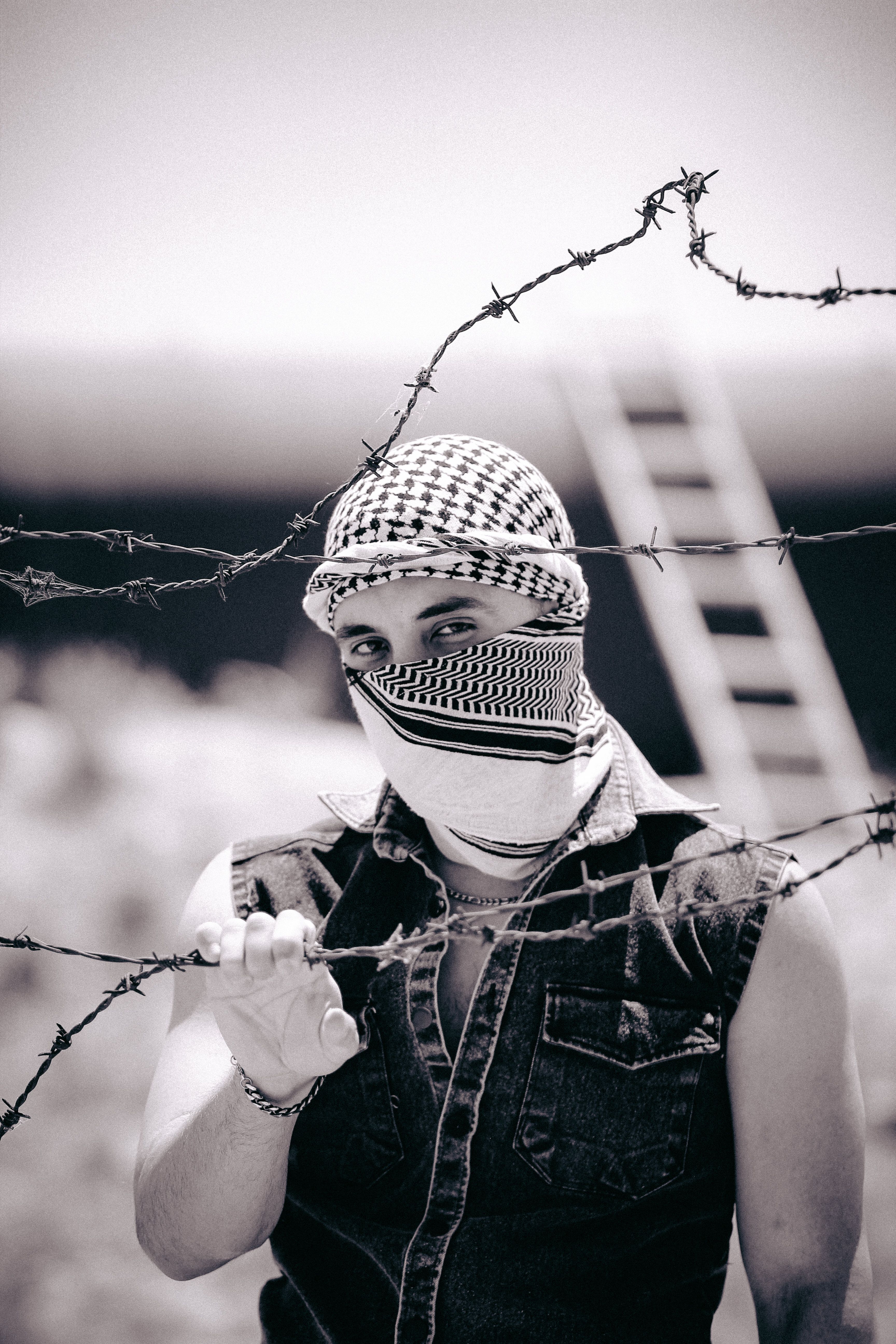 Portrait of a person outdoors behind barbed wire, evoking themes of isolation.