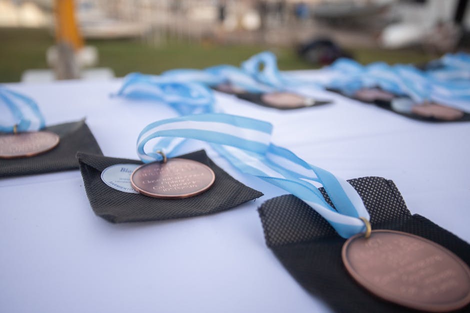 Close-up of bronze medals with blue ribbons laid out on a table at an outdoor ceremony in Mar del Plata, Argentina.