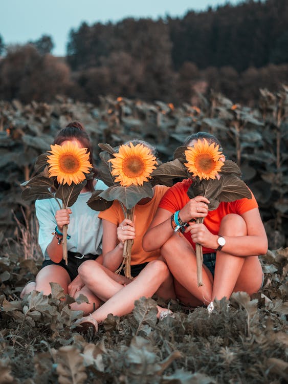 Three Women Holding Sunflowers