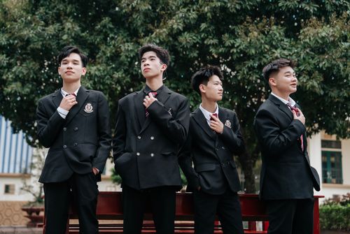 Free Group of four students in formal school uniforms standing confidently outdoors with trees in the background. Stock Photo