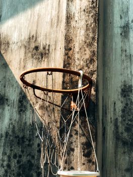 Close-up of a rusty basketball hoop with a shadow on a weathered wall, evoking nostalgia.
