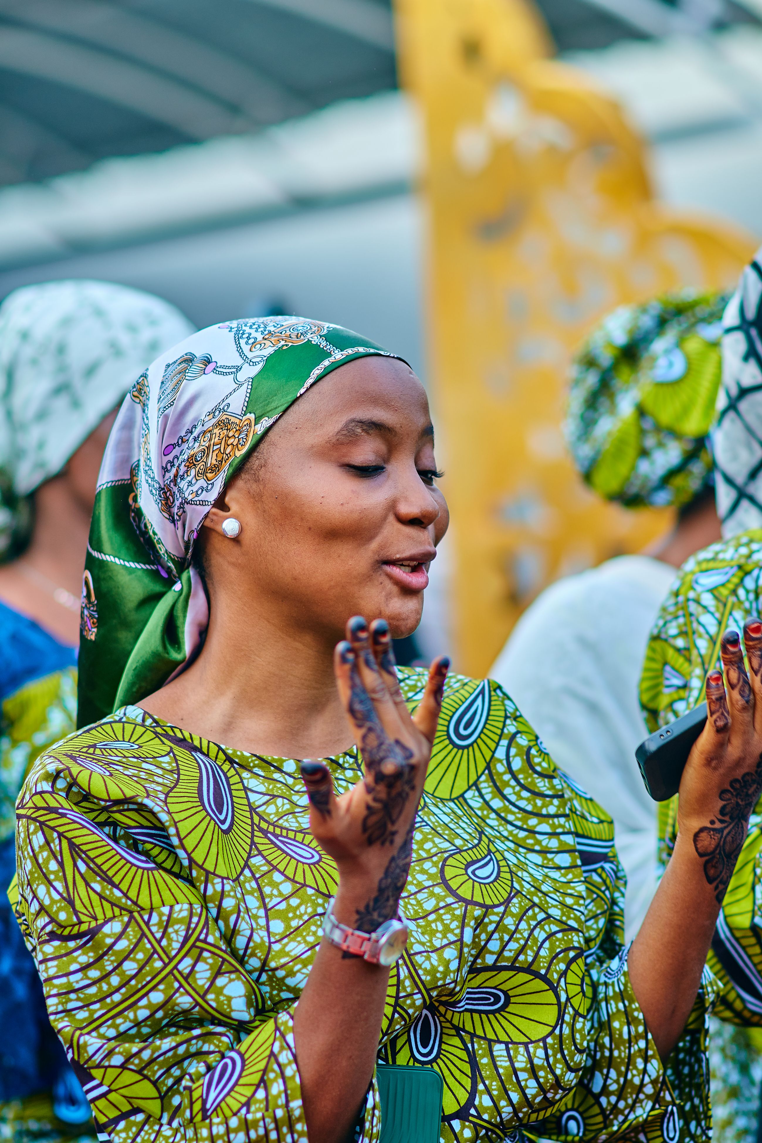 Woman in vibrant attire with henna, expressing joy during a cultural festival.