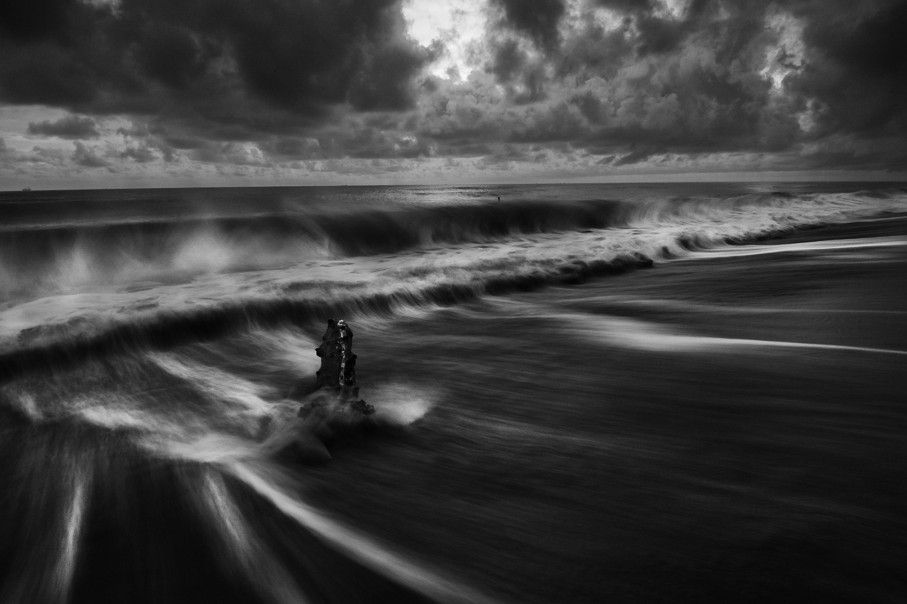 Captivating black and white seascape with stormy clouds and crashing waves.