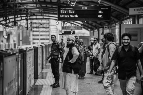 Free Passengers and a security guard waiting at a train platform in Dhaka, Bangladesh. Stock Photo
