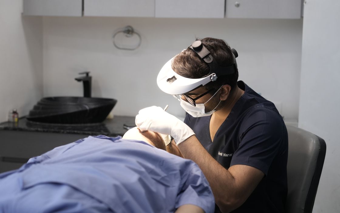 A dermatologist performing a procedure in a clinical setting in Delhi, India.