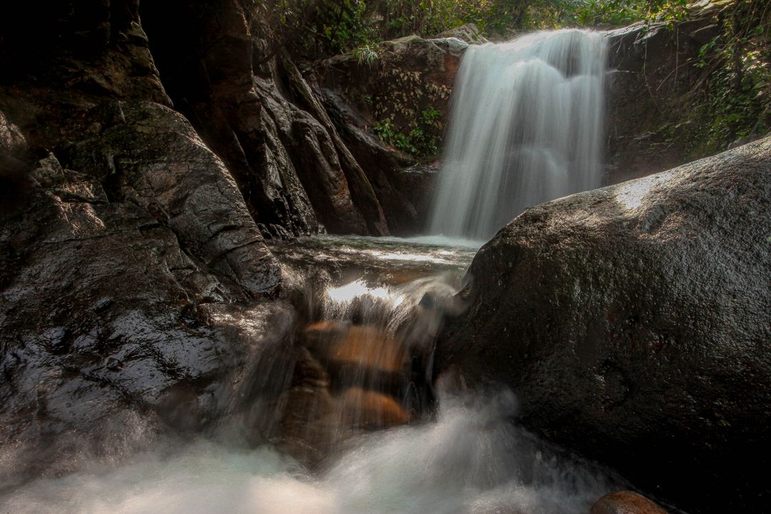Serene Waterfall Flowing Over Rocks in a Forest · Free Stock Photo
