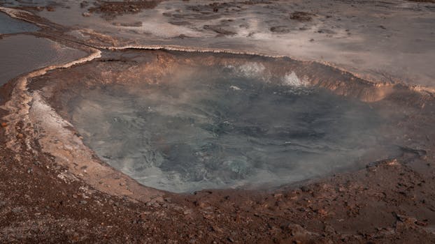 A steaming geothermal hot spring in Iceland's rugged landscape, showcasing natural beauty and volcanic activity.