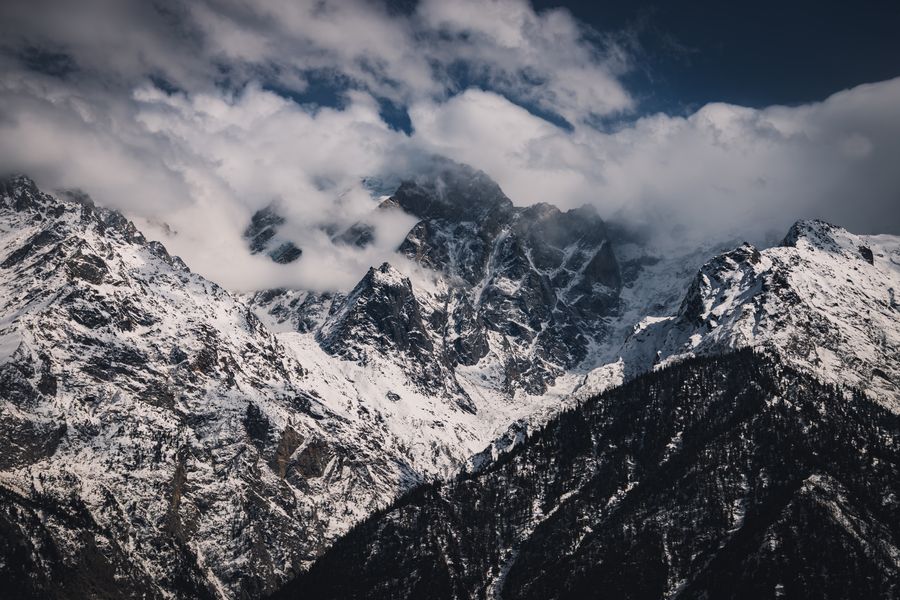 Breathtaking view of the snow-capped Himalayan peaks with clouds enveloping the mountains.
