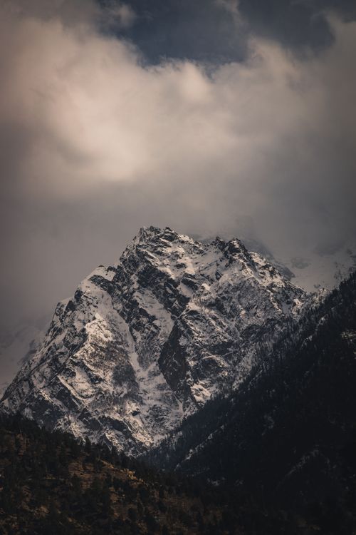 Free Explore the breathtaking beauty of a snow-capped peak in the Himalayas against a dramatic cloudy sky. Stock Photo