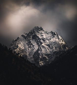 A dramatic and stunning view of snow-capped Himalayan peaks under a moody sky.