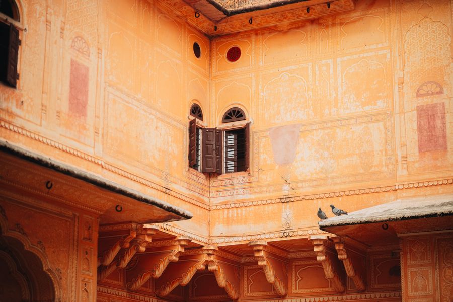 A serene view of traditional Rajasthani architecture with pigeons on a ledge in Jaipur, India.