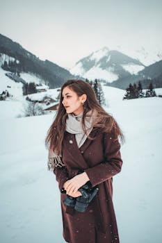 雪山风景中，一位身着冬装的时尚女子优雅伫立