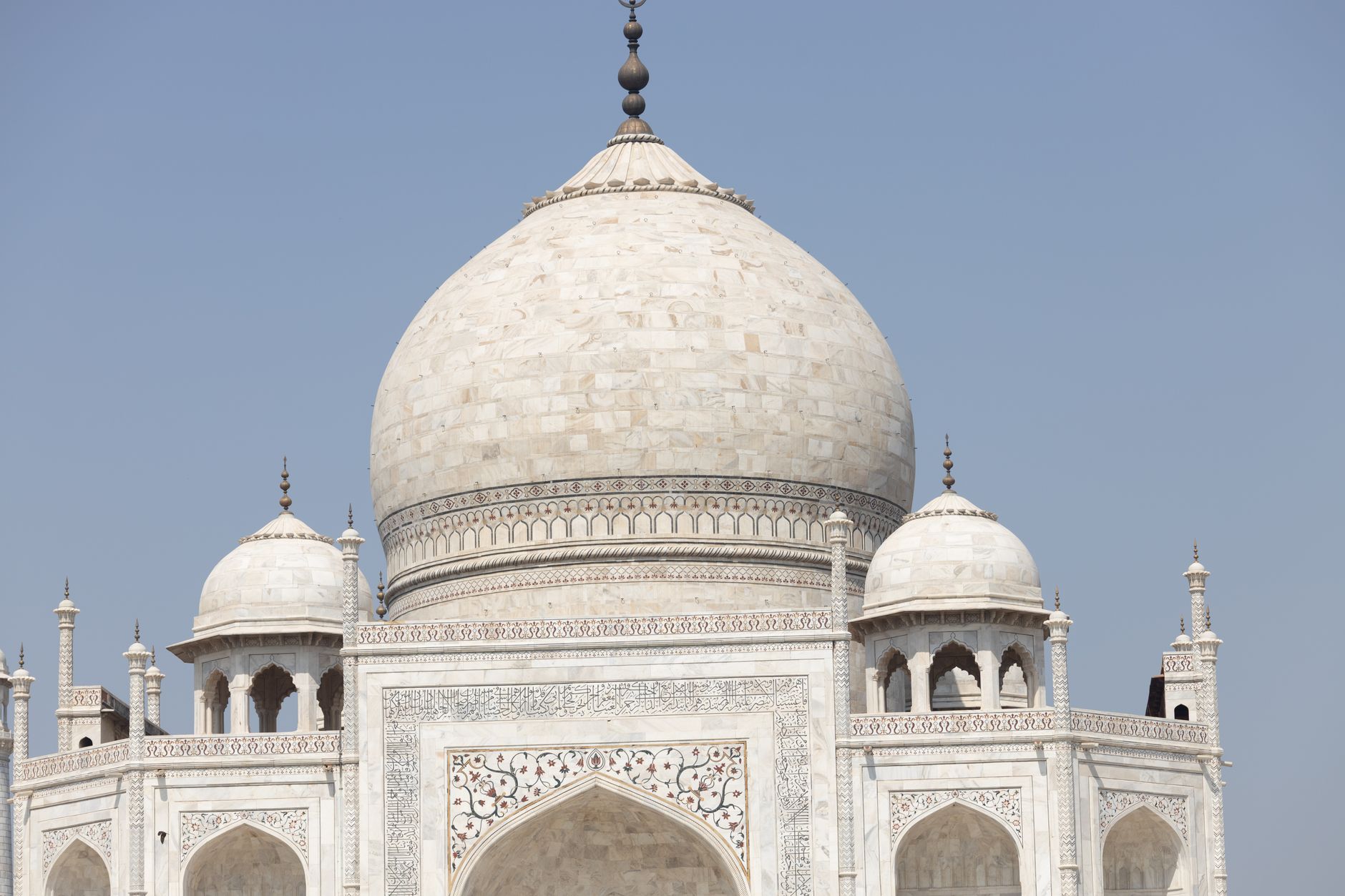 Close-up view of the iconic Taj Mahal's intricate architecture against a clear blue sky.