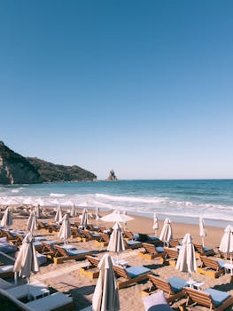 Sunny beach scene with umbrellas and chairs, perfect for summer relaxation.