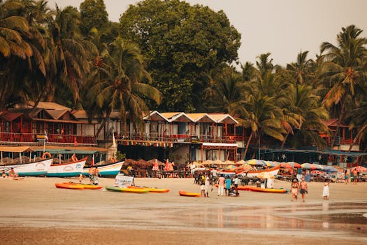 Lively beachfront scene with colorful boats, sunbathers, and lush palm trees under a warm afternoon sun.