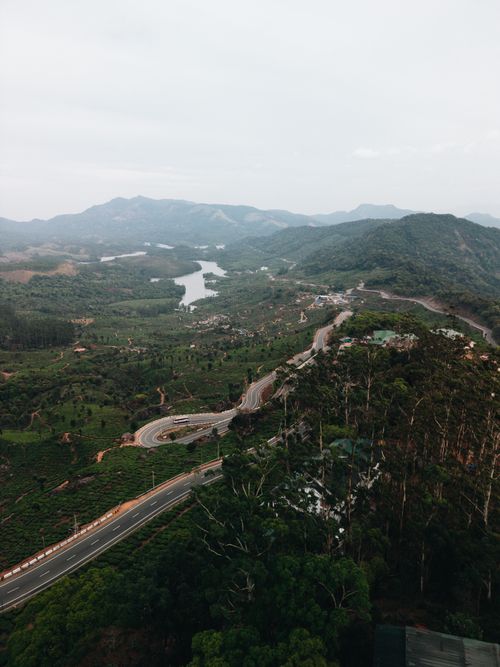 Free A stunning aerial view of curving roads amidst lush green hills and distant mountains. Stock Photo