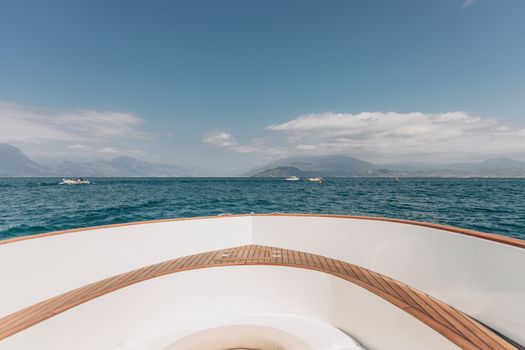 Experience the serene beauty of Lake Garda from a yacht with distant mountains under a clear sky.