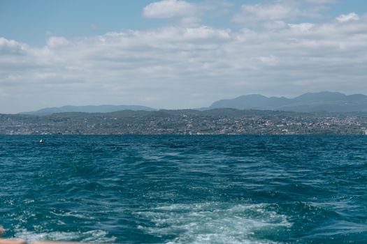 Breathtaking view of Lake Garda with rolling hills and a clear sky in the background.
