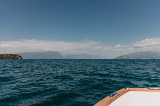 Peaceful view of Lake Garda with mountains in the background on a sunny day.