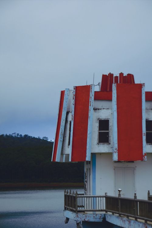 Free A unique building with red and white stripes stands by a lake under overcast skies, showcasing a distinct architectural style. Stock Photo