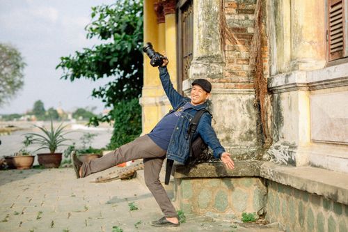 Free Happy photographer playfully poses outdoors against an old building. Stock Photo
