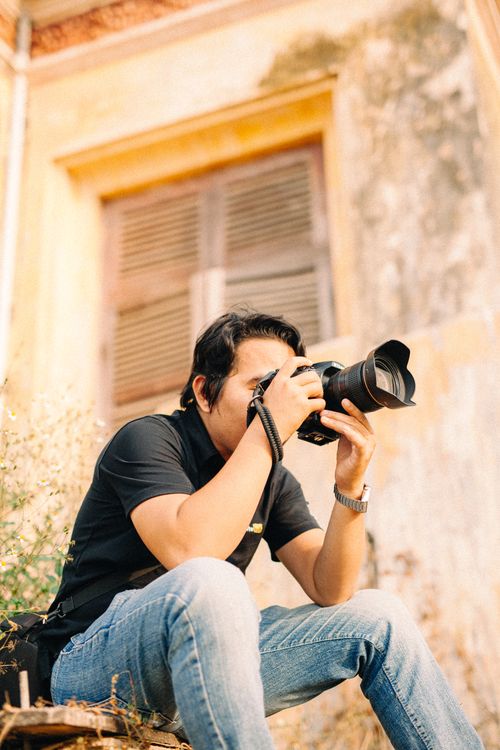 Free Adult male photographer taking pictures outdoors with DSLR camera. Stock Photo