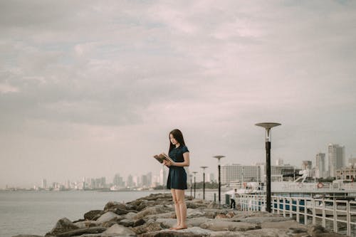 Photo Of Woman Reading Book On Top Of Rock