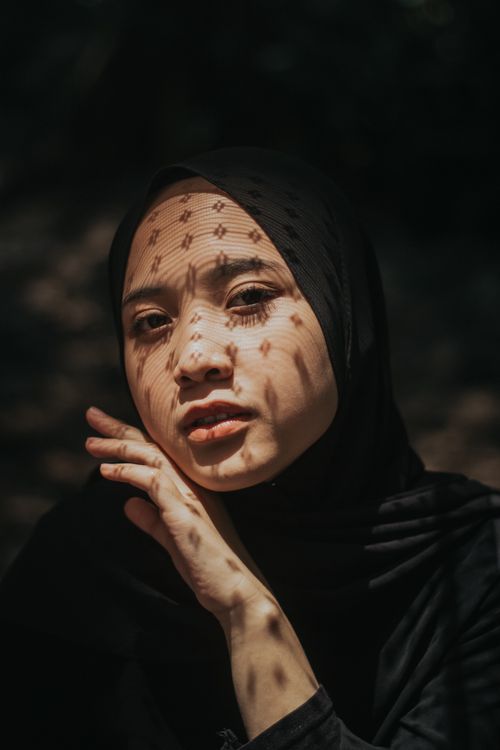 Free A thoughtful portrait of a woman in a hijab with artistic shadows on her face. Stock Photo