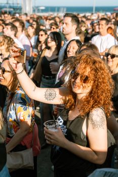A vibrant outdoor concert with a joyful crowd enjoying the music under the sun.